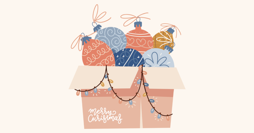 Cardboard box overflowing with Christmas decorations with an baubles, Christmas tree balls, ornaments and string of lights with lettering text - Merry Christmas.