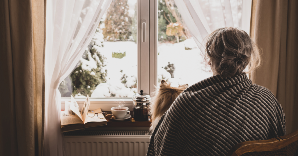 Woman looking at window at winter landscape.